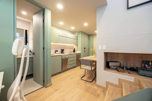 A compact kitchen with modern appliances, a dining area with a chair, and a small workspace with a typewriter.