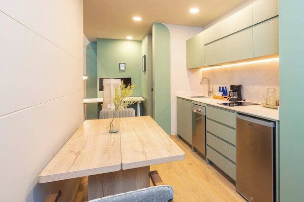 A compact kitchen with a wooden table, a coffee machine, and a dishwasher.