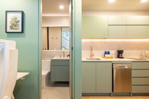 Una cocina moderna con armarios verde claro, lavavajillas y cafetera.
