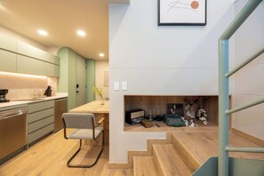 A modern kitchen with a dining area, a staircase, and a small alcove with decorative items. - Digital Nomad Paradise 1BR unit with A/C in Manila (Medellín)