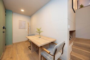 A dining area with a wooden table and chairs, a vase with a plant, and a staircase to the right. - Digital Nomad Paradise 1BR unit with A/C in Manila (Medellín)