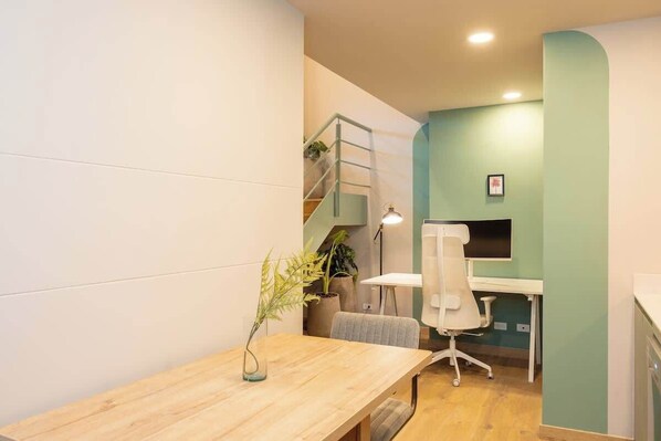 Un espacio de oficina moderno con un escritorio de madera, una silla de oficina blanca, una pequeña escalera y una planta en maceta.