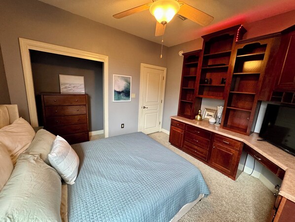A bedroom with a bed, dresser, and built-in shelving unit.