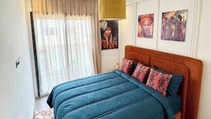 A modern bedroom with a large bed, a headboard, and a window with curtains.