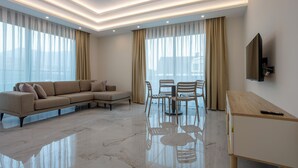 Una sala de estar moderna con un sofá modular, una mesa de comedor con sillas y un televisor montado en la pared.