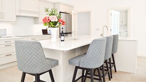 Una cocina moderna con armarios blancos, una isla central con taburetes y un jarrón de flores.