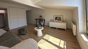 A spacious loft bedroom with a large window, a bed, a desk, and a chair. - Studio under the roof - Marché (LA ROCHELLE)