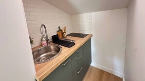 A compact kitchen with a sink, wooden countertop, and green cabinets. - Studio under the roof - Marché (LA ROCHELLE)