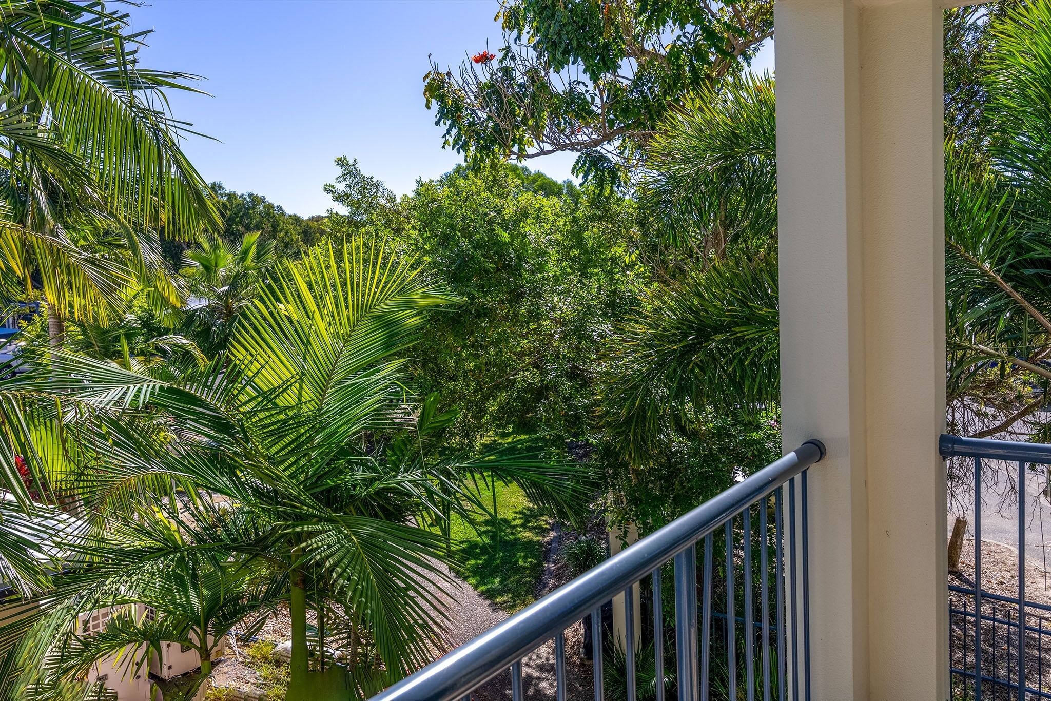 Un balcone con ringhiera in metallo che si affaccia su un giardino rigoglioso, ricco di alberi e piante.
