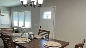 Une salle à manger avec une table en bois, six chaises et un lustre.