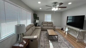 Un salon moderne avec un canapé, une table basse, un téléviseur et un ventilateur de plafond.