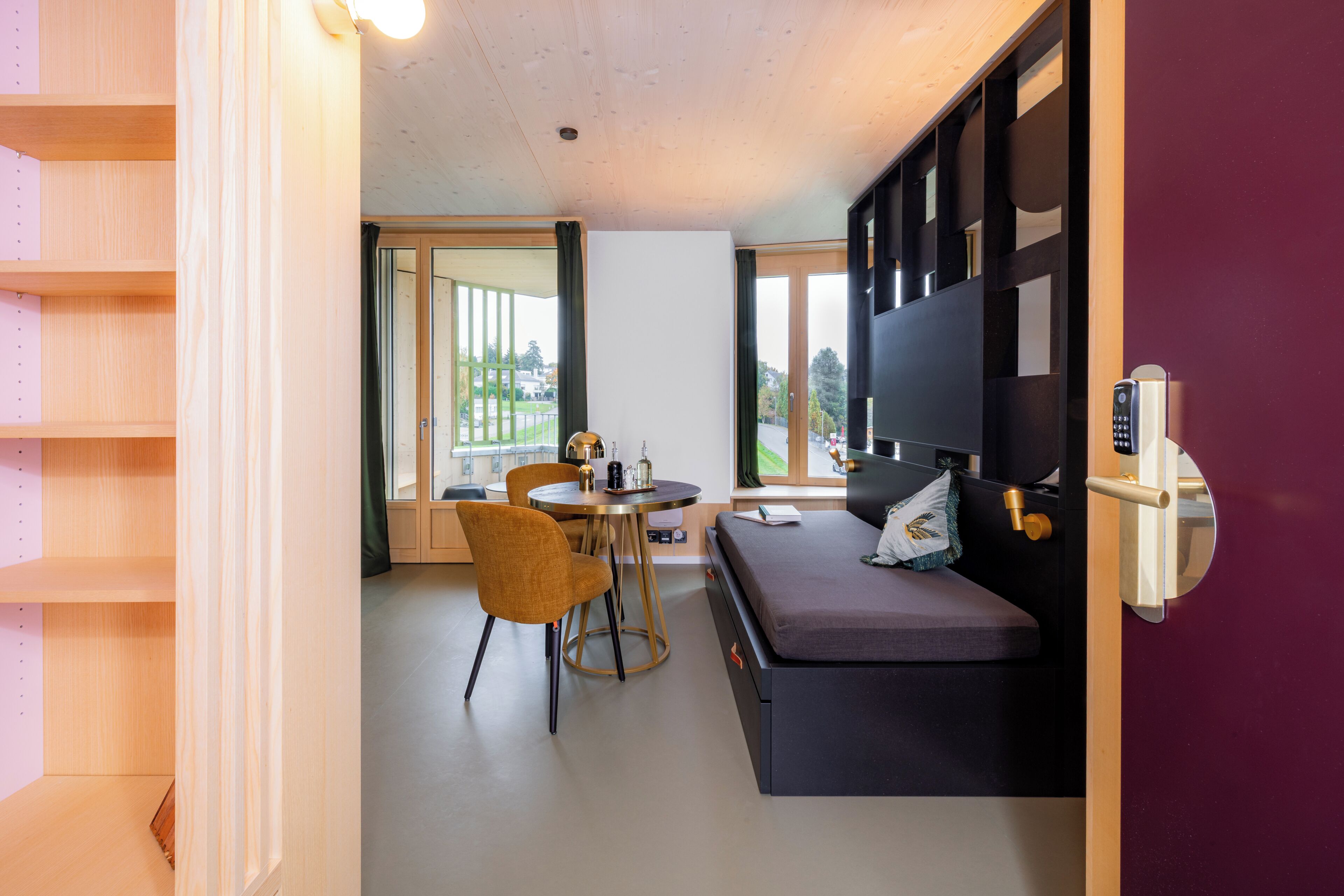 Een moderne kamer met een bank, een tafeltje en een stoel. Een raam biedt uitzicht op het omliggende landschap.
