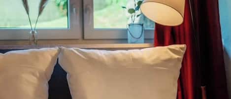 En seng med hvide puder og en læselampe.