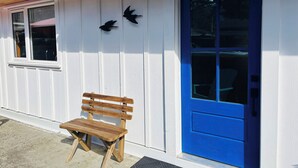 Un banco de madera frente a un edificio con una puerta azul y una ventana.