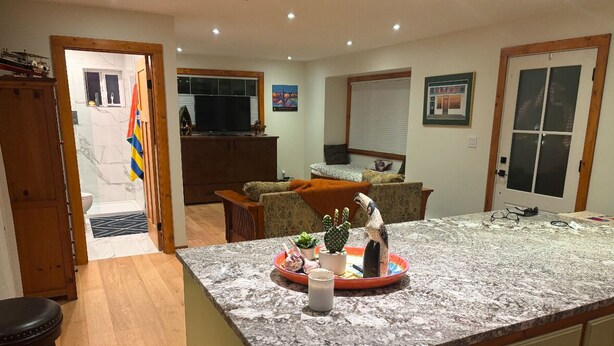Una cocina con encimera de mármol, armarios de madera y una zona de comedor con mesa y sillas.