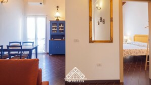 A spacious room with a dining area, a blue cabinet, a large mirror, and a bed with a yellow headboard.