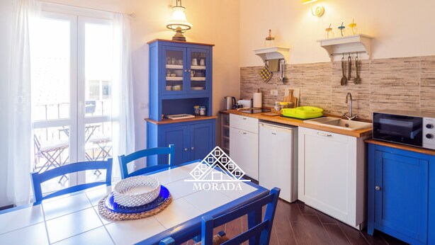 A compact kitchen with a dining area, featuring a blue cabinet, a microwave, and a sink.