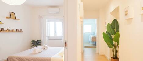 A bedroom with a bed, bedside table, and a potted plant.