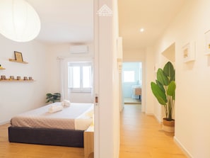 Un dormitorio con cama, mesita de noche y una planta en maceta.