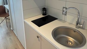 A modern kitchen with a stainless steel sink, a black induction cooktop, and a built-in oven. - Comfort Studio in a Premium Residence- Sport/cinema (Huningue)