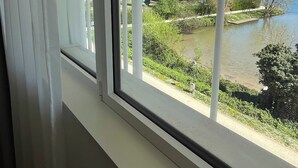 A window with a view of a river, greenery, and buildings in the distance. - Comfort Studio in a Premium Residence- Sport/cinema (Huningue)