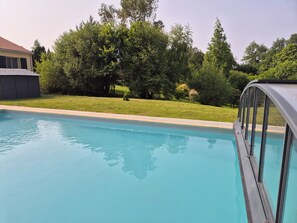 Une piscine offrant une vue dégagée sur la végétation environnante, avec une maison en arrière-plan.