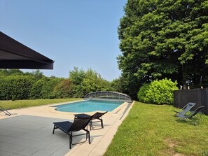 A backyard with a swimming pool, two lounge chairs, and a covered patio area. - House with swimming pool, pets welcome. 3300-metre fenced park (La chapelle montbrandeix)
