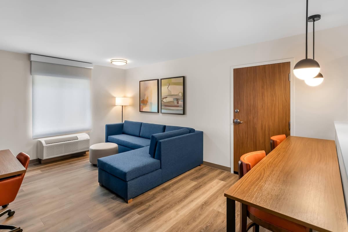 A modern living room with a sectional sofa, a wooden dining table, and a wooden door.