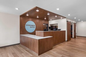 A reception desk with a sign reading 'EVERHOME SUITES,' a laptop on the counter, and a door leading to a storage area. - Everhome Suites Stockbridge Atlanta (Stockbridge)