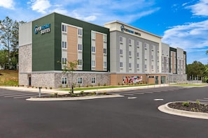 Un hôtel moderne avec une façade en pierre, plusieurs étages et un parking.
