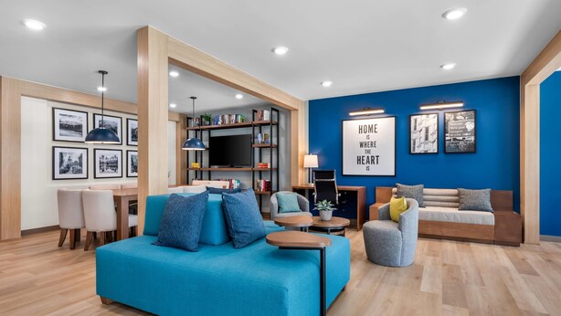 Un salon moderne avec un mur d’accent bleu, un canapé, une table basse, une bibliothèque et des tableaux encadrés.
