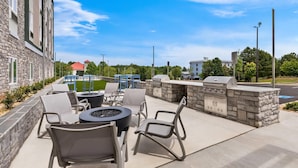 Une terrasse extérieure avec des murs en pierre, un barbecue et des sièges.