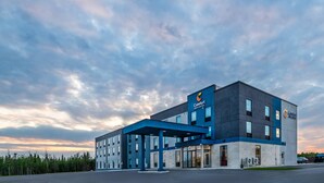 A modern hotel with a blue and grey facade, large windows, and a covered entrance. - Comfort Inn & Suites (Cochrane)