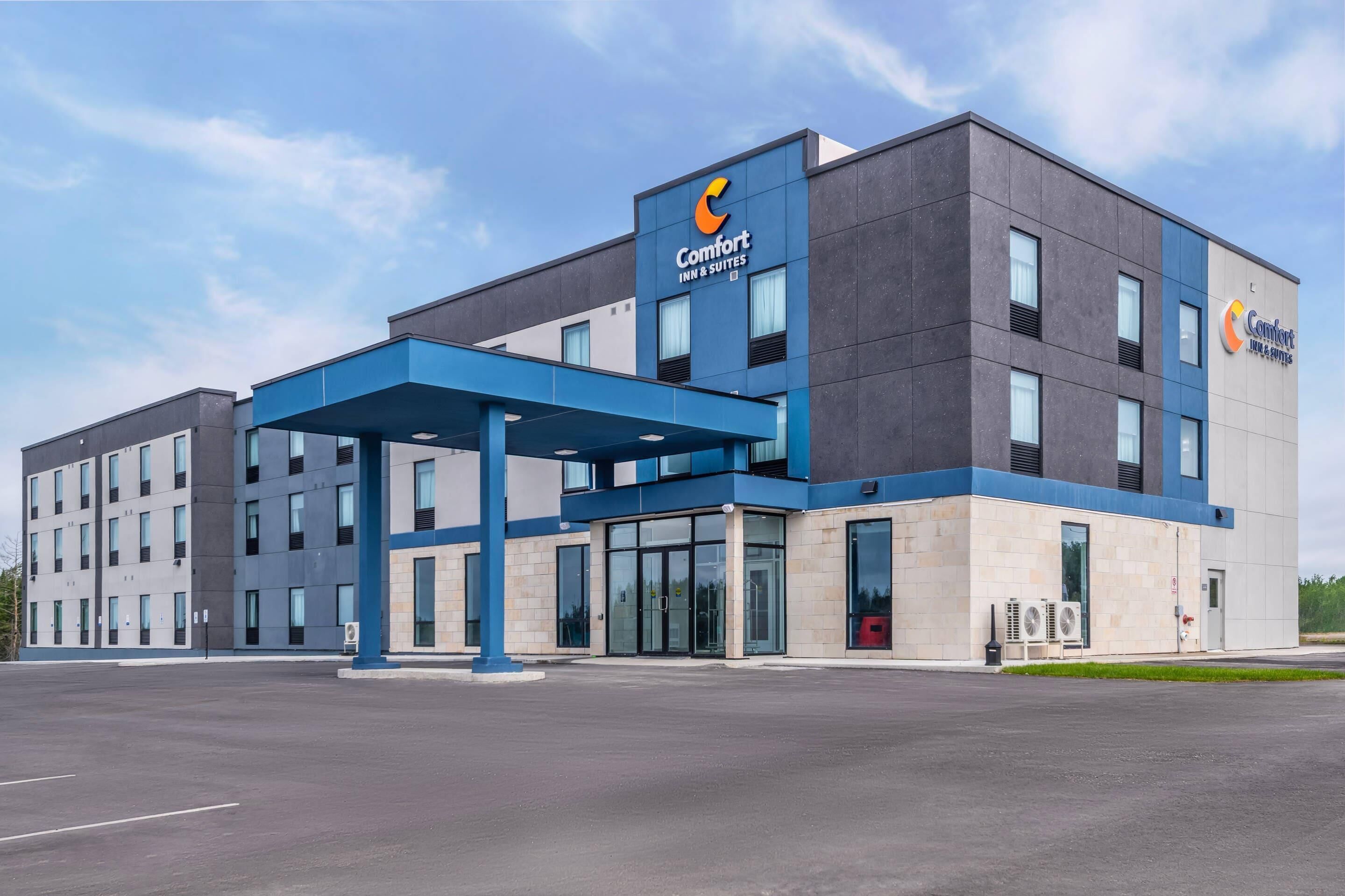 A modern Comfort Inn & Suites hotel with a blue and grey facade, large glass entrance, and a covered outdoor area.