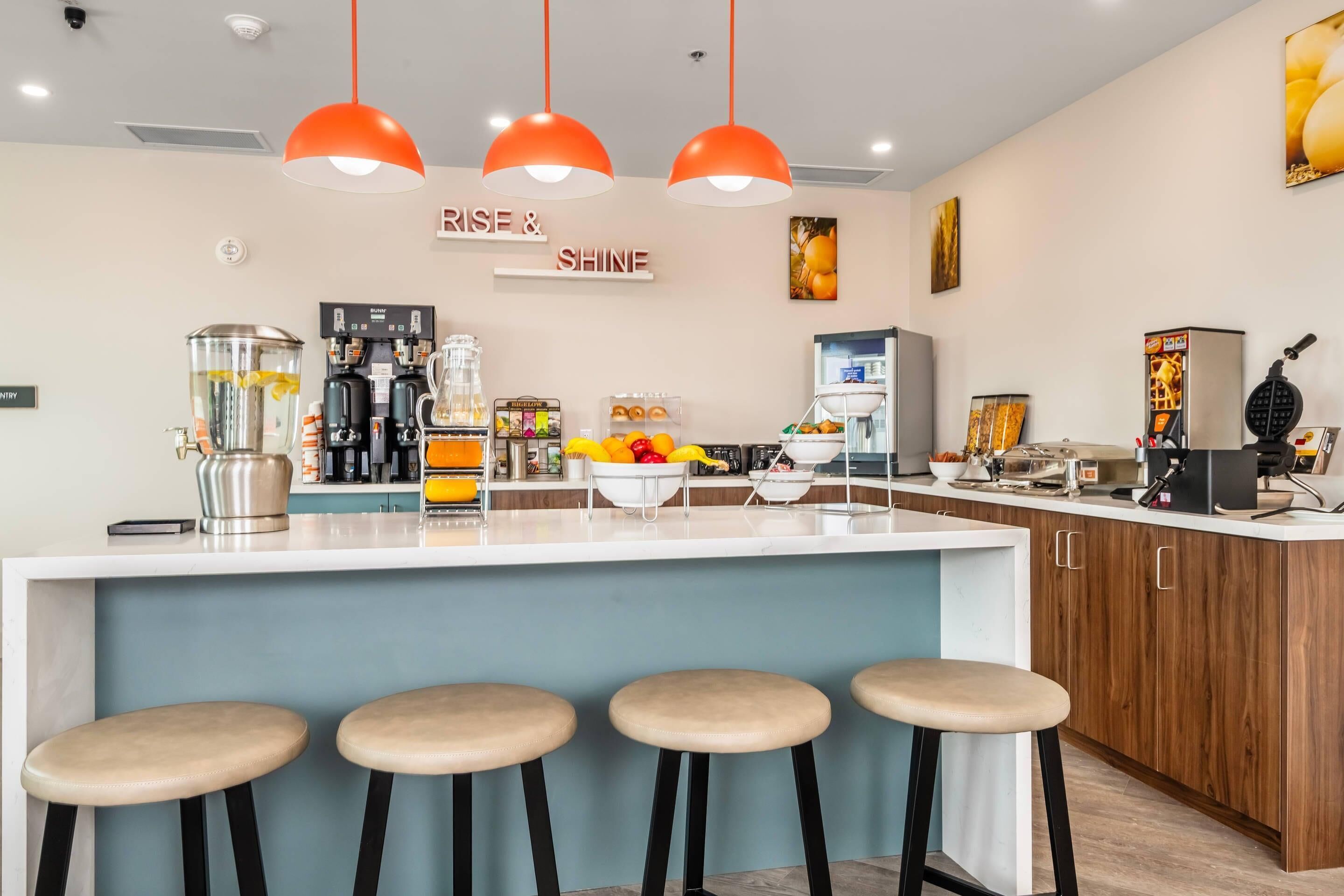 A modern kitchen with a central island, bar stools, and a coffee machine.