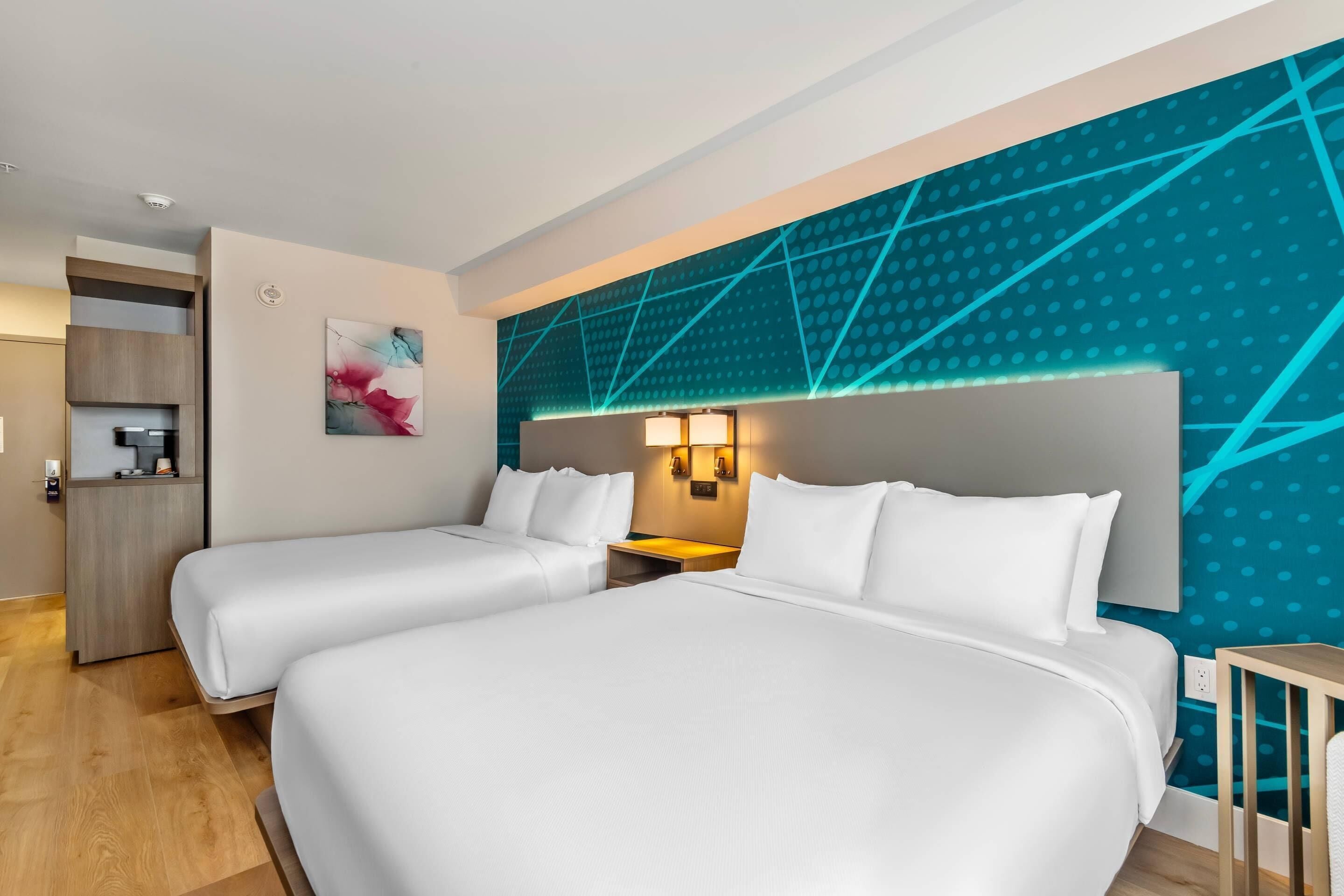 Ein Hotelzimmer mit zwei Betten, einem Schreibtisch und einer Küchenzeile.