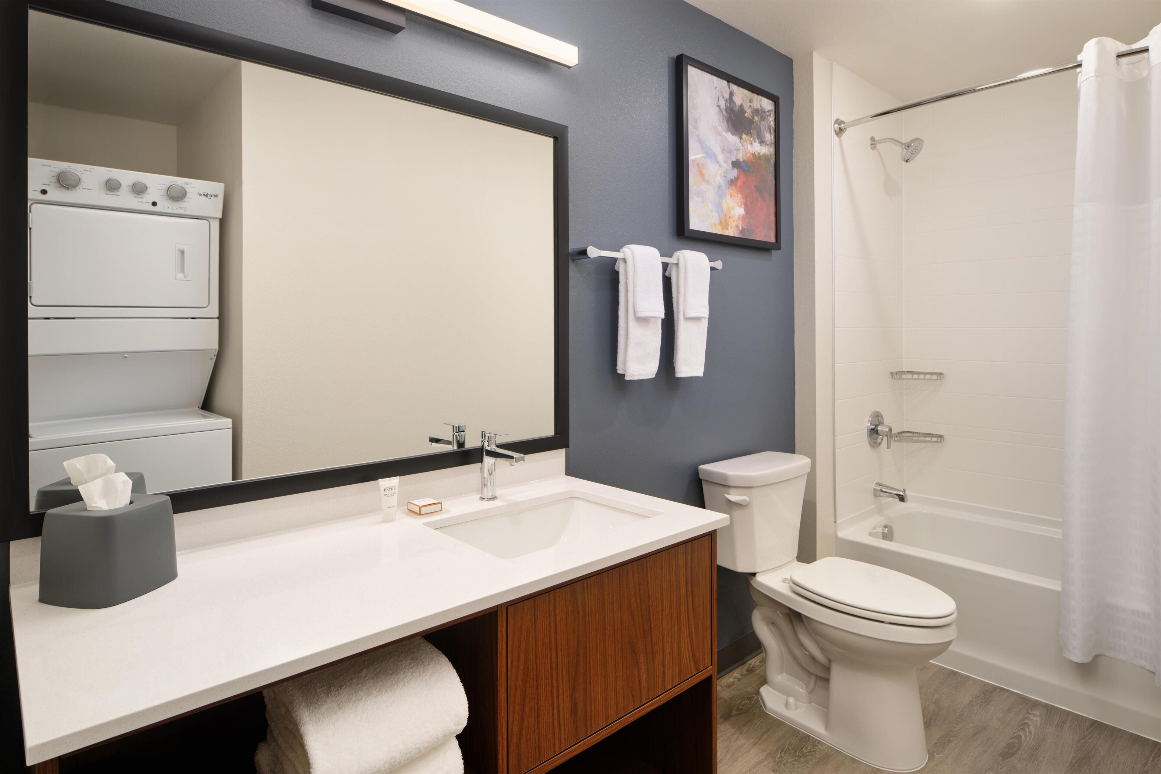 A bathroom with a sink, mirror, toilet, and shower.