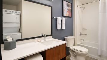 A bathroom with a sink, mirror, toilet, and shower.
