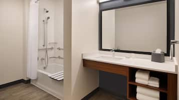 A modern bathroom with a bathtub, a sink, a mirror, and a towel rack.