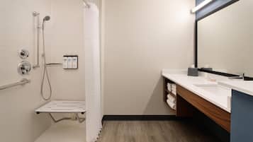 Un baño moderno con ducha, lavamanos, espejo y toallero.