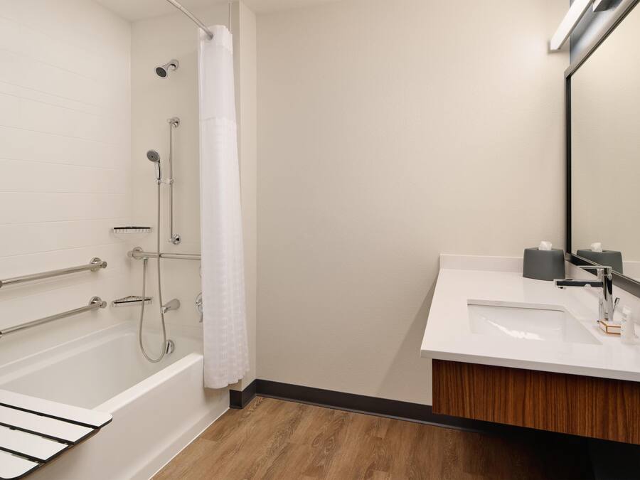 A modern bathroom with a bathtub, shower, and vanity with a mirror.