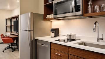 Una cocina moderna con refrigerador, microondas, cafetera y lavamanos.