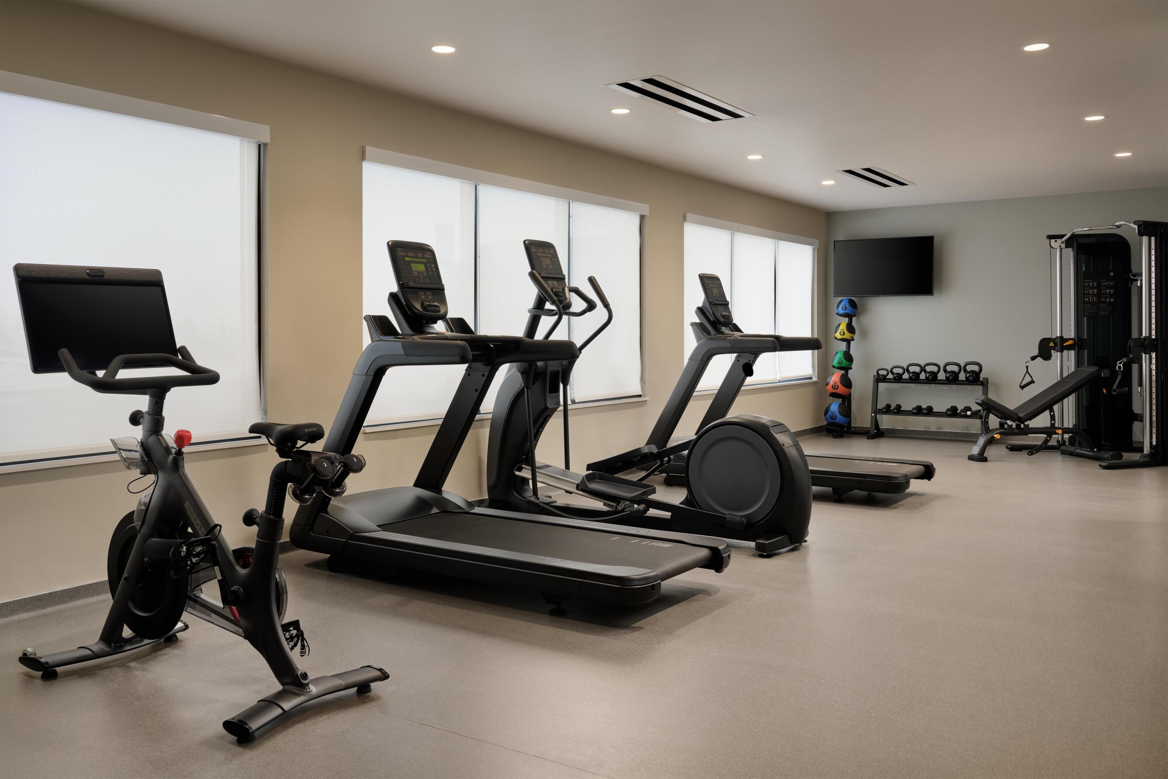 Une salle de sport équipée de tapis de course, d’un appareil elliptique et de machines de musculation.