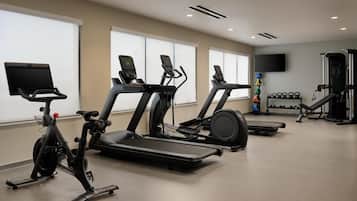 Une salle de sport équipée de tapis de course, d’un appareil elliptique et de machines de musculation.