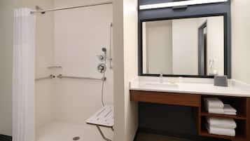 A bathroom with a shower, a sink, a mirror, and a towel rack.