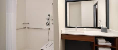 A bathroom with a shower, a sink, a mirror, and a towel rack.