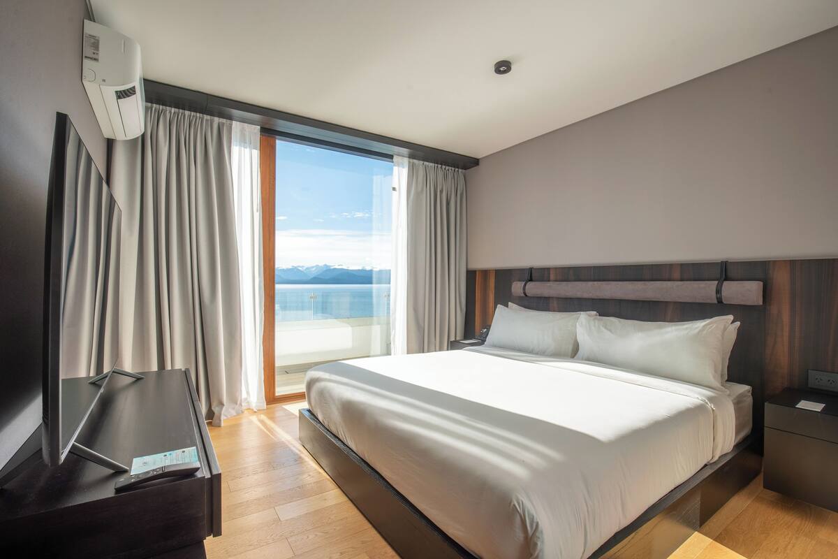 Ein modernes Hotelzimmer mit einem großen Bett, einem Flachbildfernseher und Meerblick.