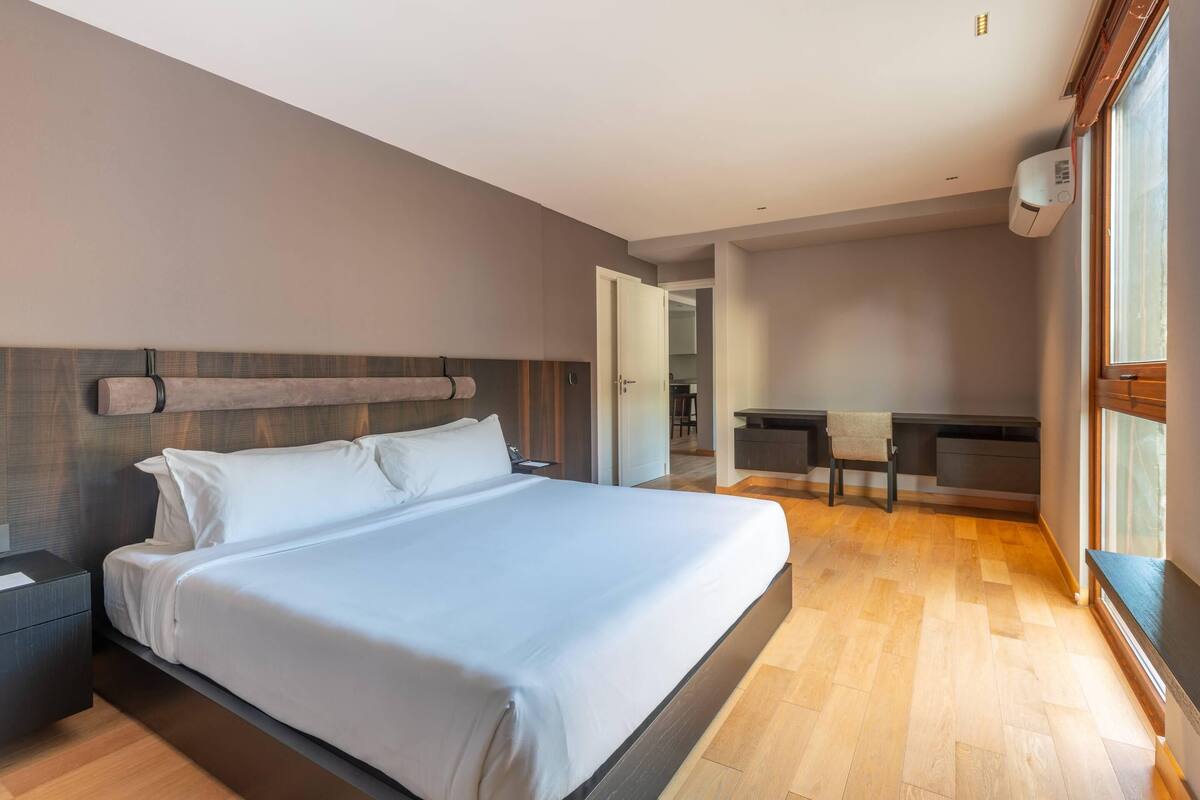 Ein modernes Hotelzimmer mit einem großen Bett, einem Schreibtisch und einem Stuhl.