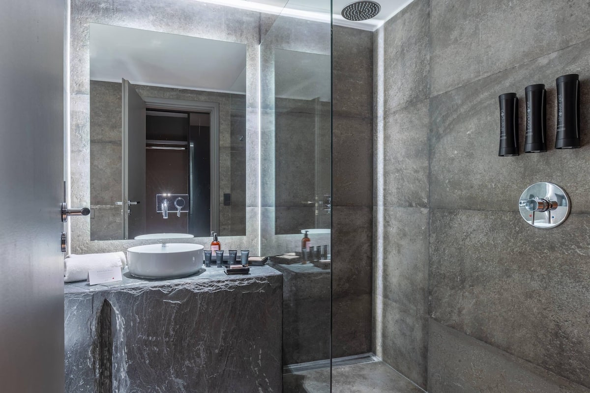 Ein modernes Badezimmer mit einem großen Spiegel, einem runden Waschbecken und einer Duschkabine.
