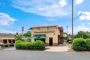 Un Starbucks Coffee con un letrero visible, un paraguas verde y un estacionamiento.